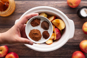 Spices for making apple butter in a white dish.