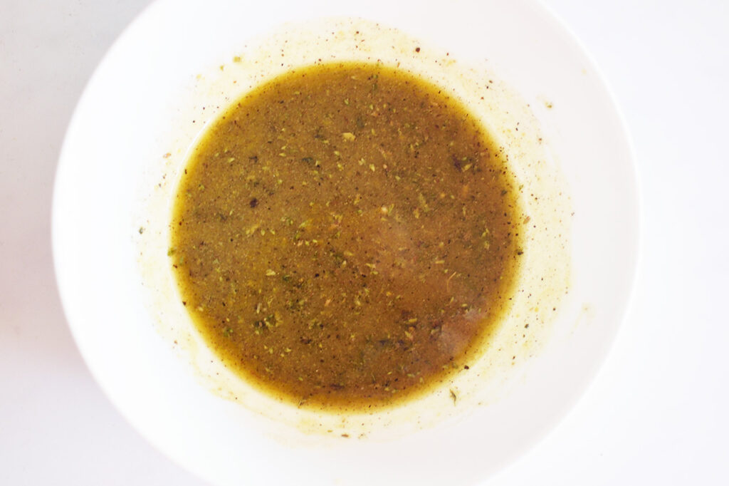 Mixed dressing for Artichoke Salad in a white bowl.