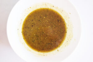 Mixed dressing for Artichoke Salad in a white bowl.