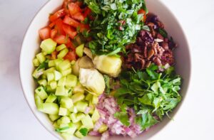 Artichoke Salad ingredients in a white mixing bowl, unmixed. Overhead focus.