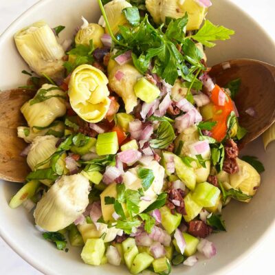 Overhead focus. Artichoke Salad in a white bowl with wood spoons.