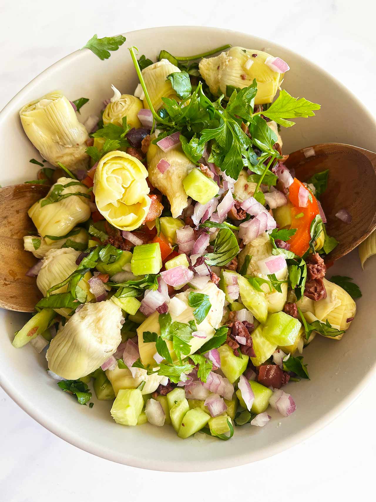 Overhead focus. Artichoke Salad in a white bowl with wood spoons.