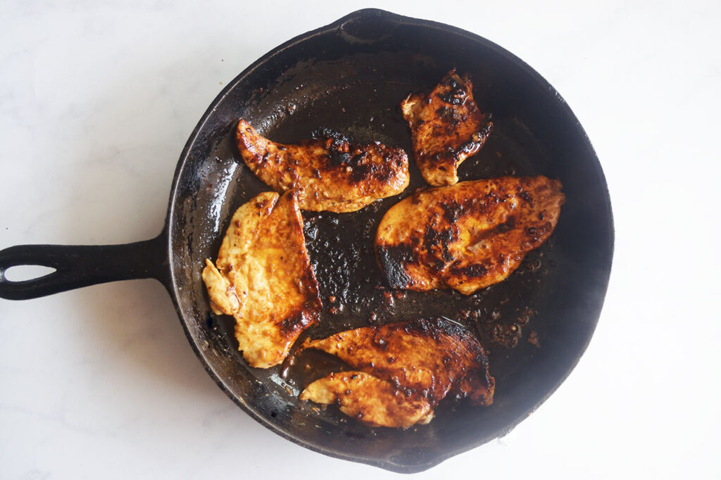 Cooked chicken pieces in a skillet.