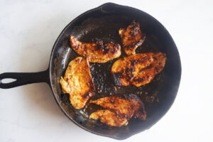 Cooked chicken pieces in a skillet.