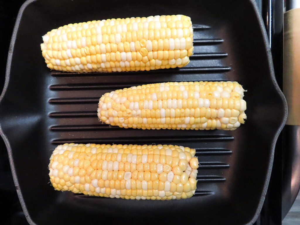 Three cobs of corn on a grill pan. Overhead focus.