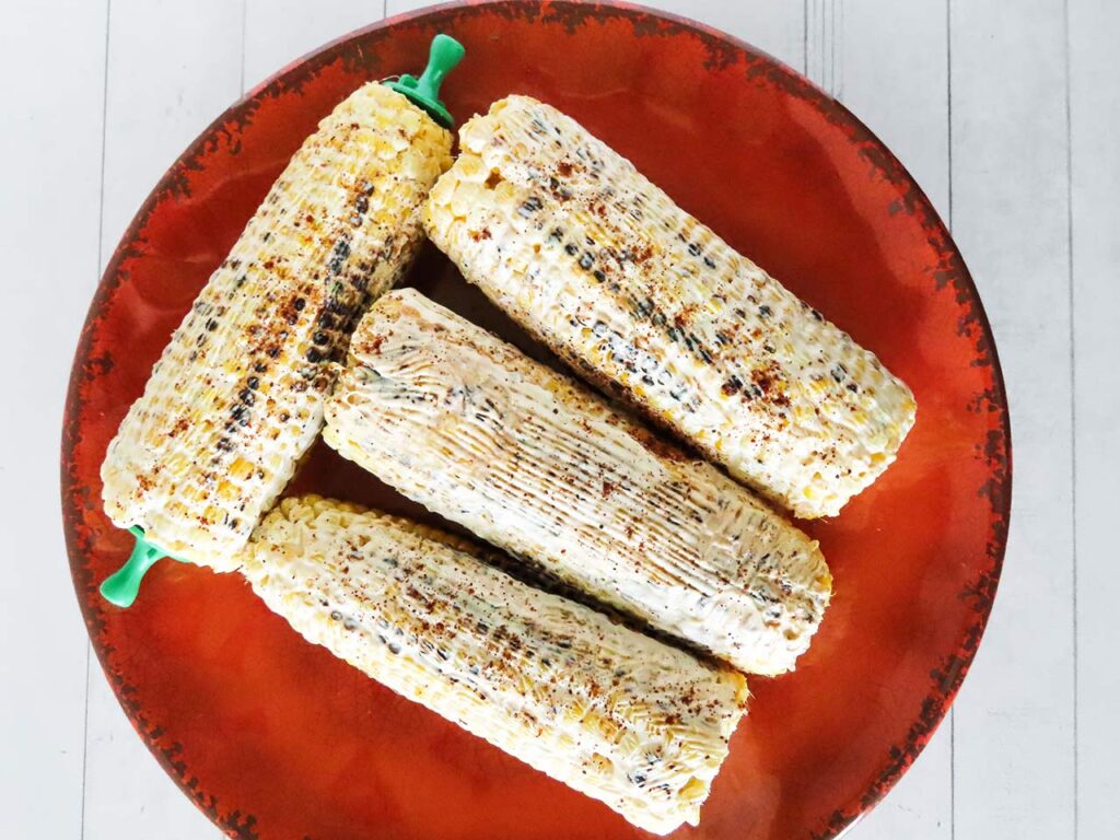 Grilled corn cobs covered in yogurt spread.