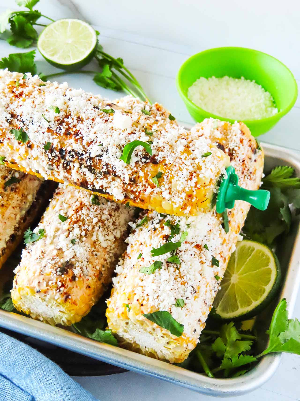 Close view of four elotes in a metal pan.