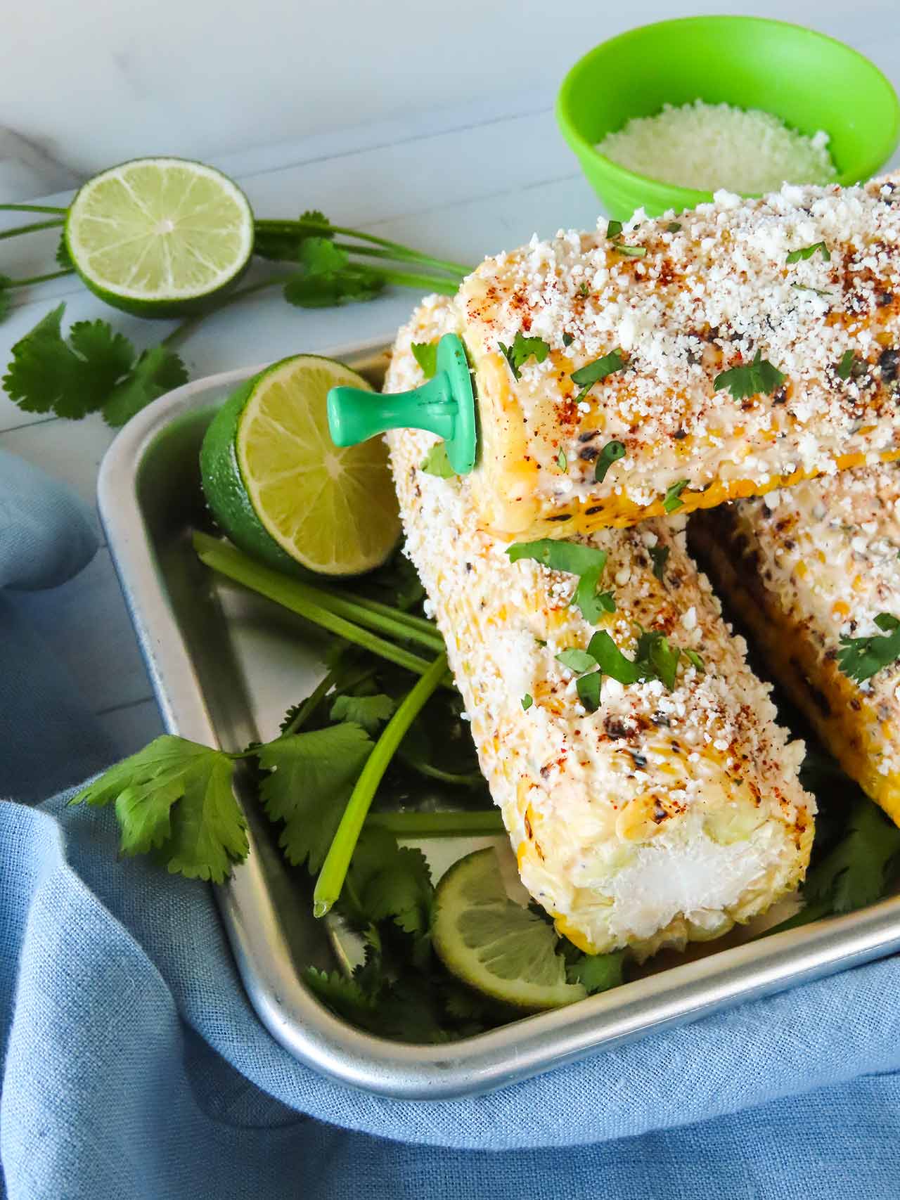 Partial side view of elotes in a metal pan.