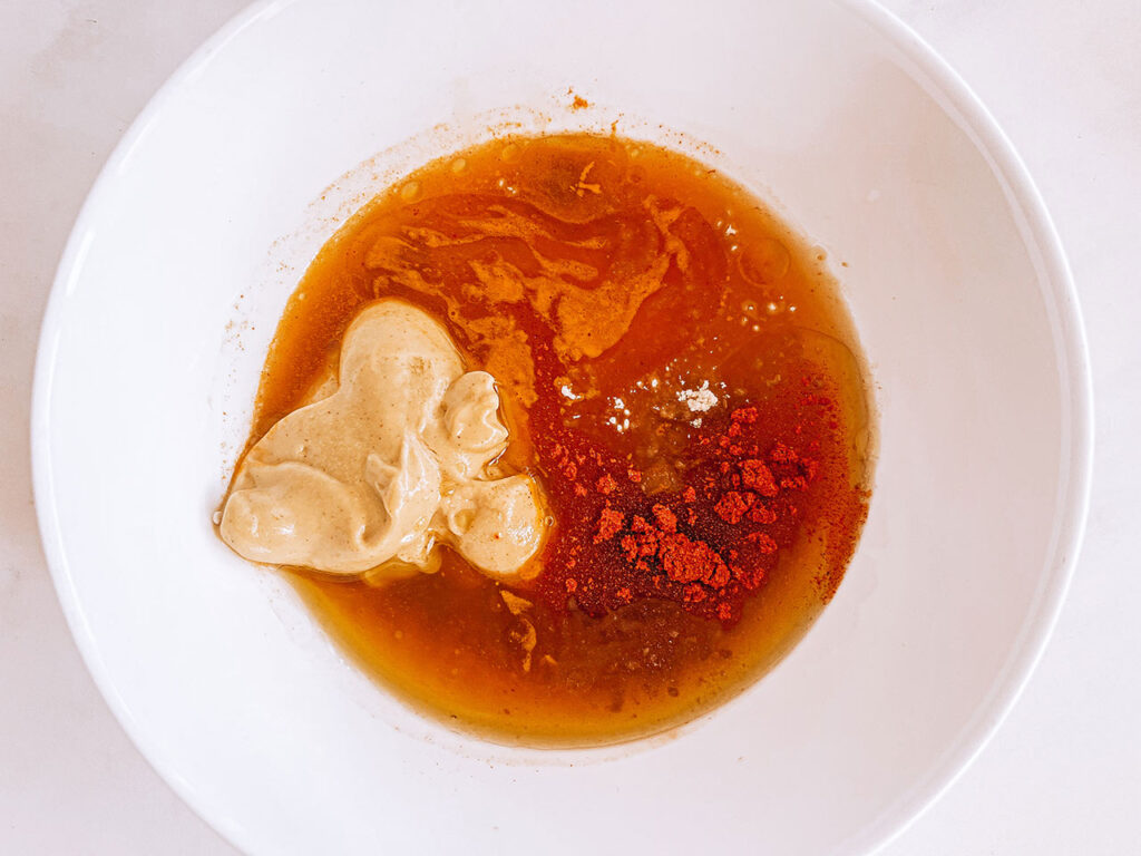 Honey mustard dressing ingredient in a mixing bowl, unmixed.