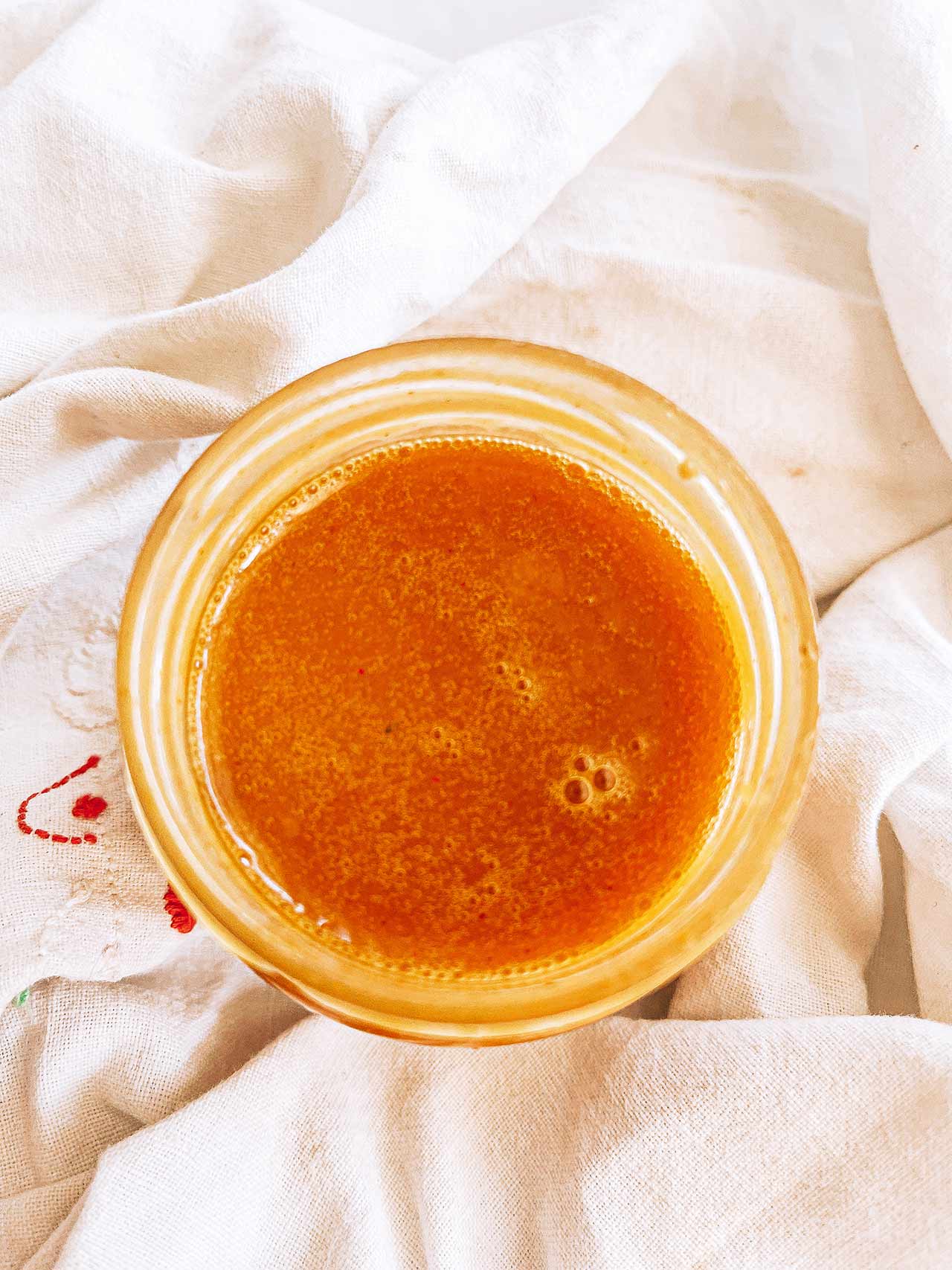 Overhead view of an open jar of honey mustard dressing.