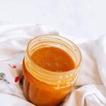 Top angled view of an open jar of honey mustard dressing.