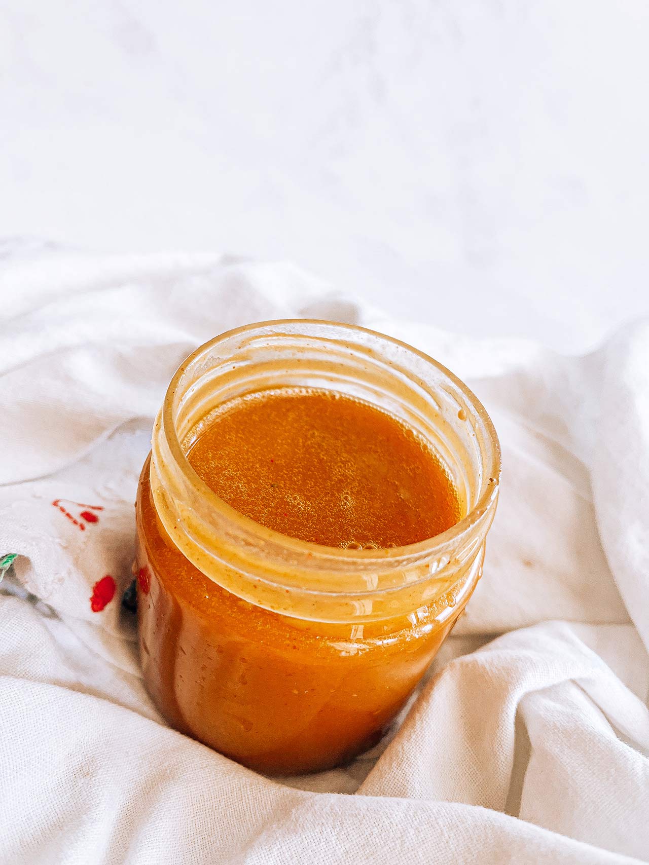 Top angled view of an open jar of honey mustard dressing.