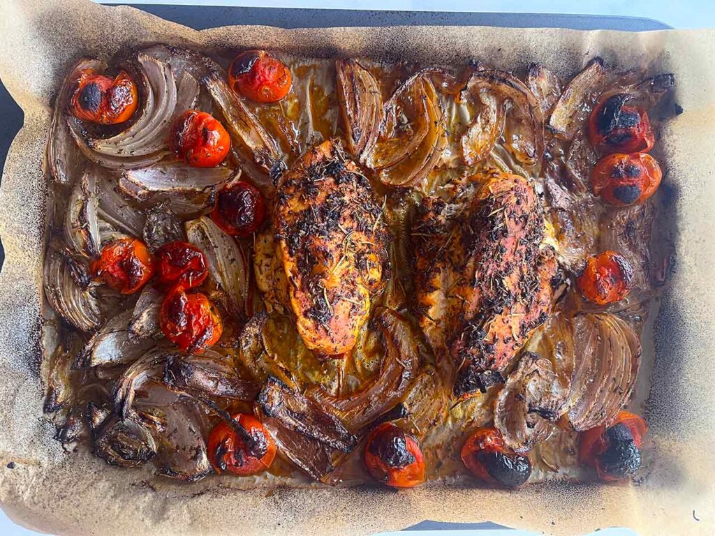 Cooked Mediterranean Sheet Pan Chicken just out of the oven. Overhead focus.