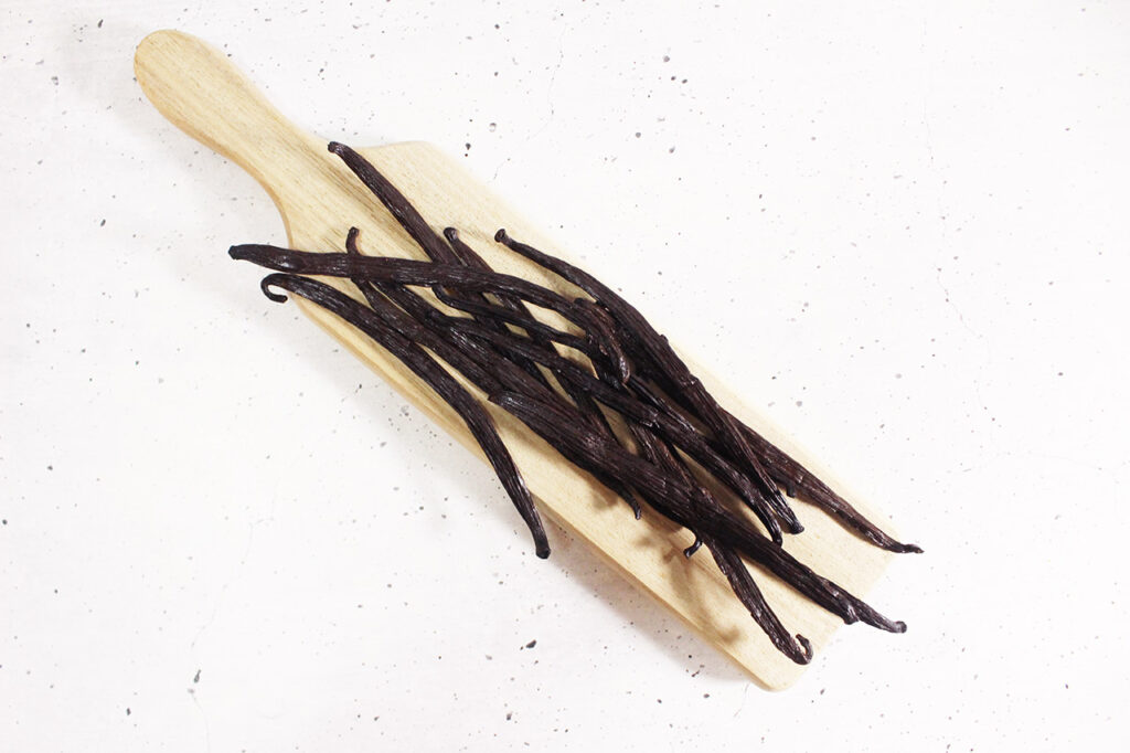Vanilla beans on a small, wood cutting board.