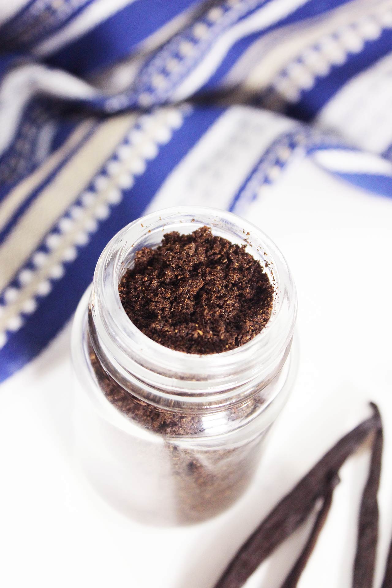 Angled, partially overhead view of a spice jar filled with vanilla powder.