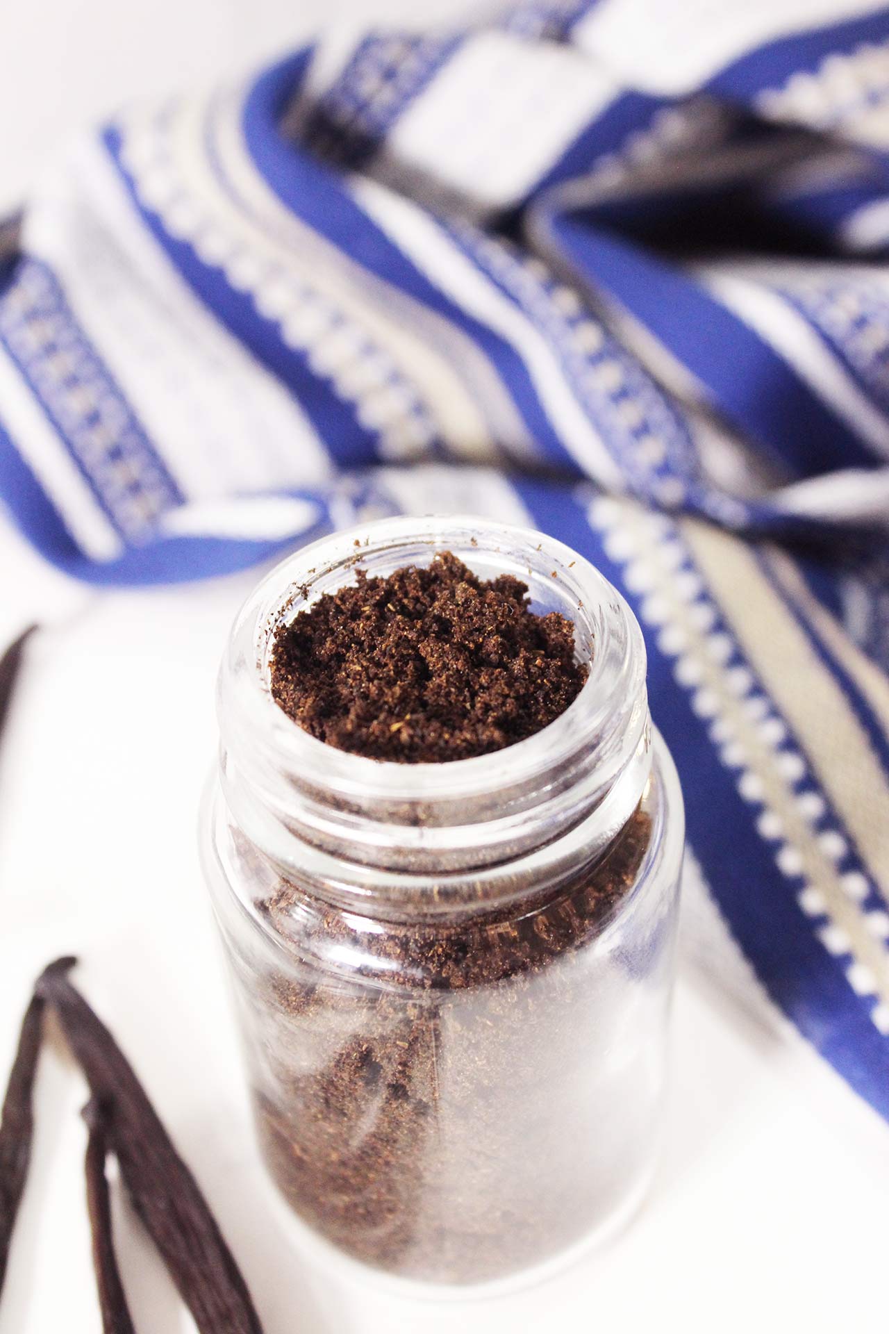 Slightly overhead view of a glass spice jar filled with vanilla powder.