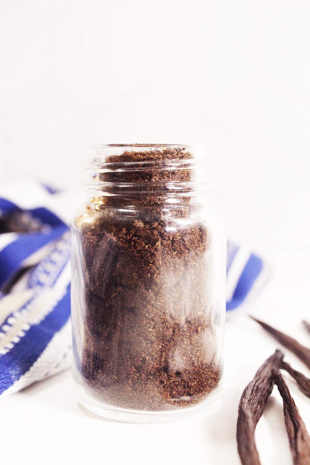 Front view, closeup of a glass spice jar filled with vanilla powder.