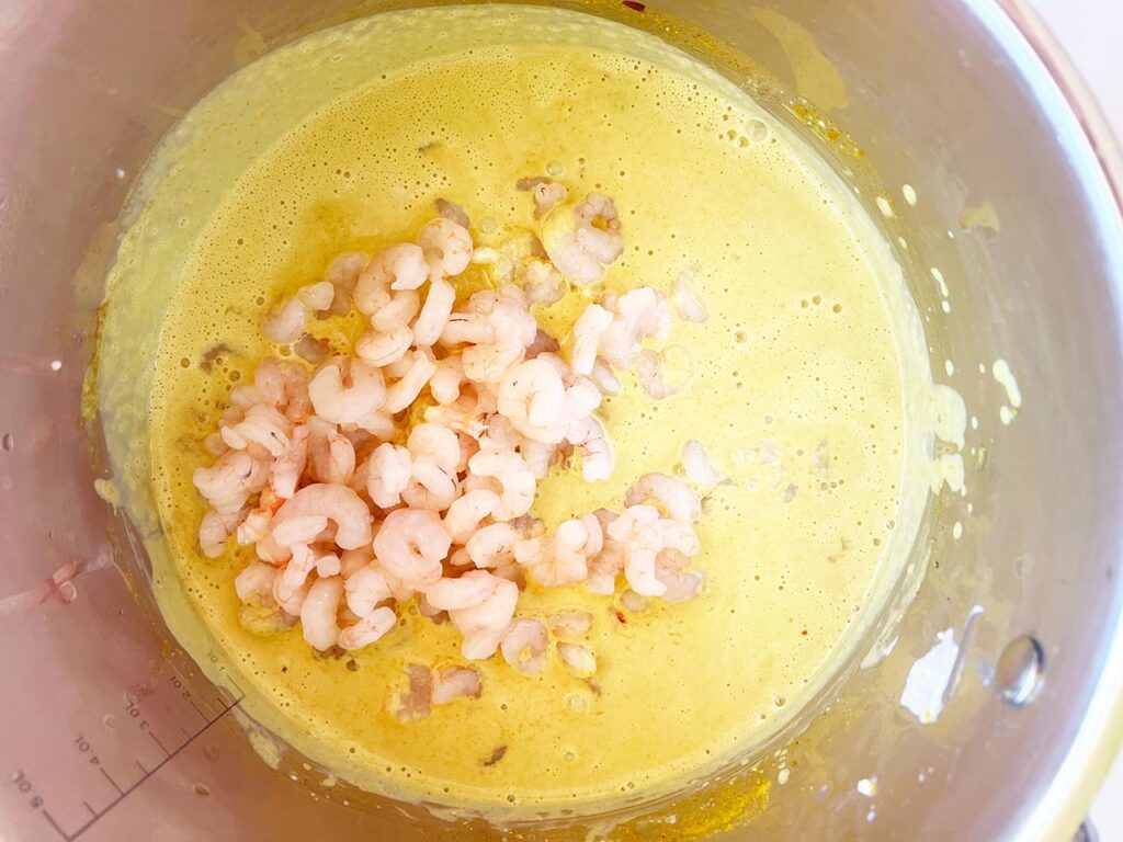 Shrimp added to curry sauce in a pot.