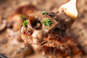 Closeup of a fork holding a bite of Creamy Mushroom Chicken.