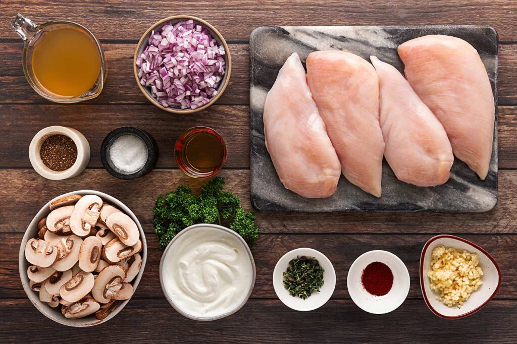 Creamy Mushroom Chicken ingredients gathered on a wooden surface. Overhead focus.