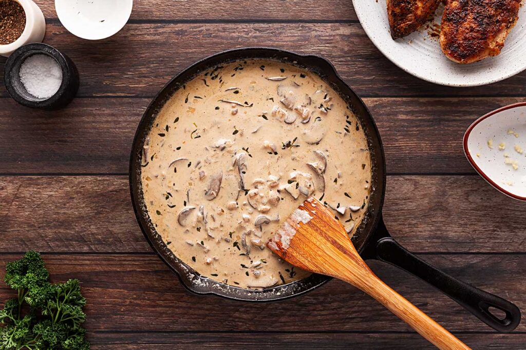 The finished creamy sauce for Creamy Mushroom Chicken, in a cast iron skillet. Overhead focus.