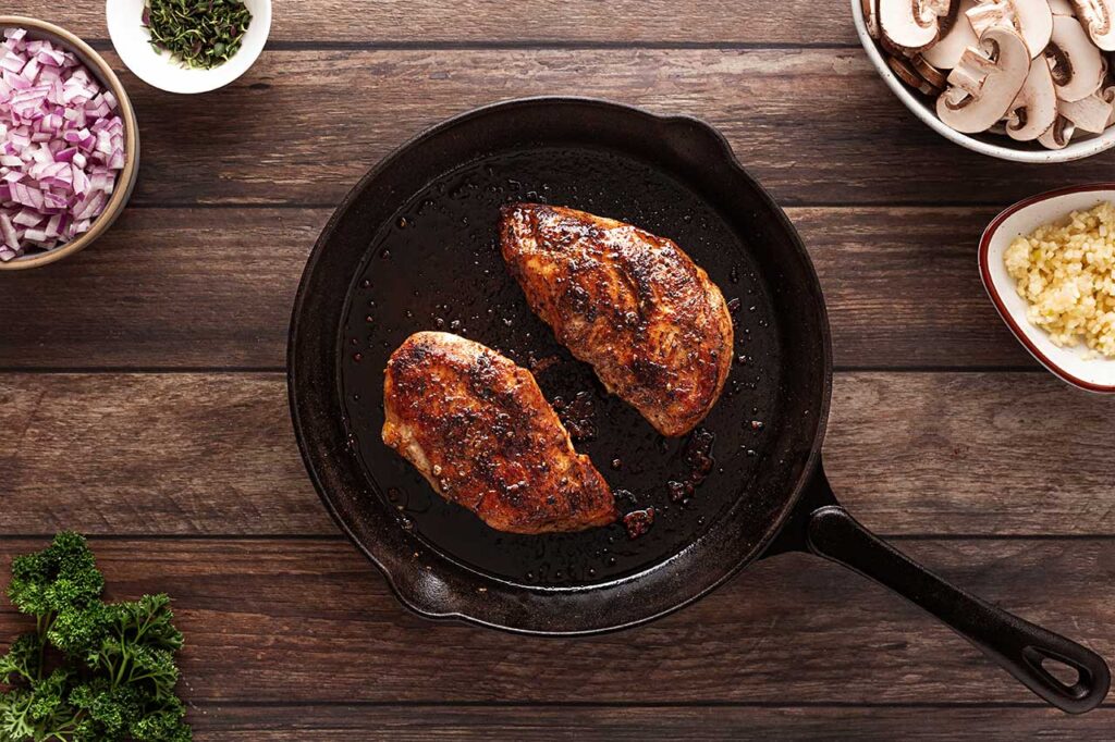 Cooked chicken breasts in a cast iron skillet. Overhead focus.