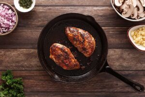 Cooked chicken breasts in a cast iron skillet. Overhead focus.