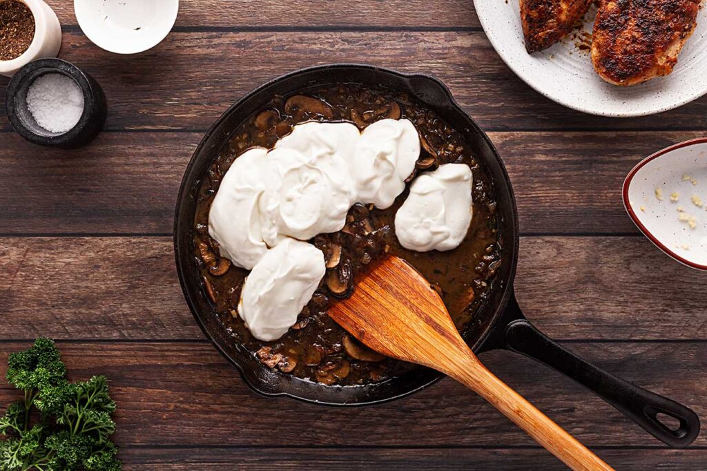 Yogurt added to a skillet of mushrooms, garlic and onions.