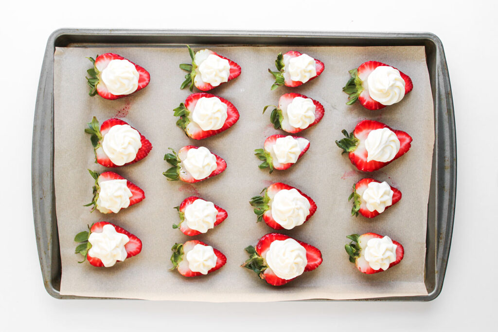 Cream cheese filling piped onto halved strawberries.