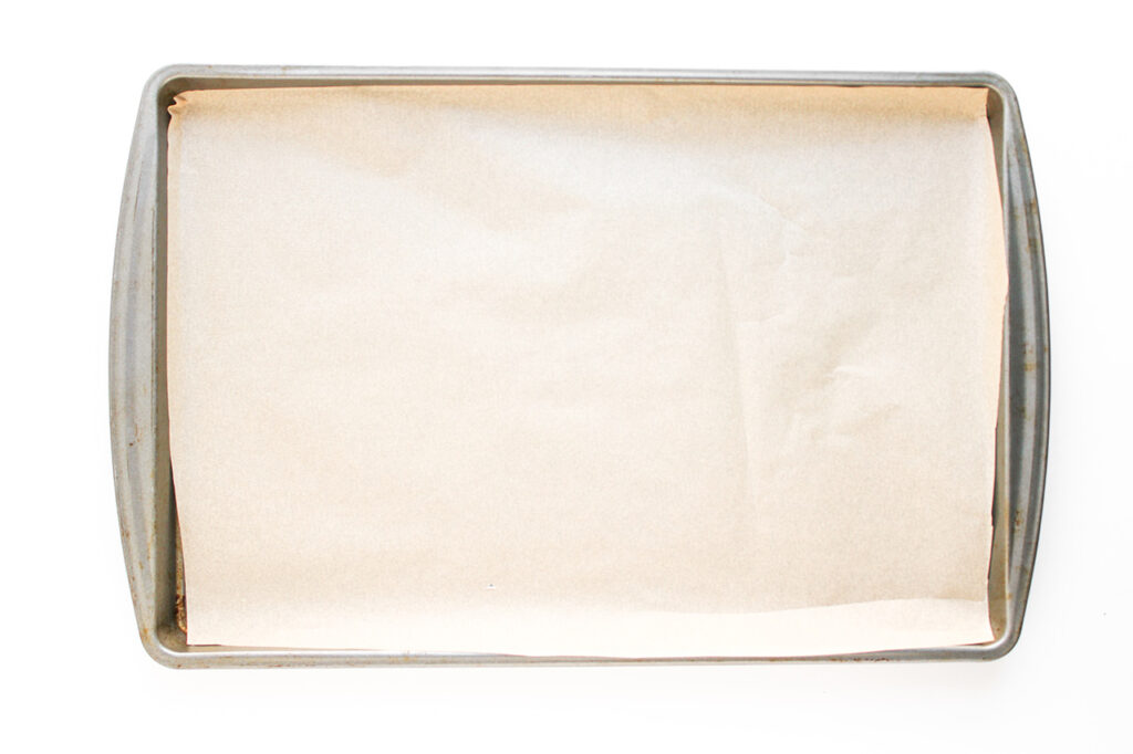 Overhead focus. A parchment-lined baking pan on a white background.