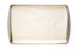 Overhead focus. A parchment-lined baking pan on a white background.