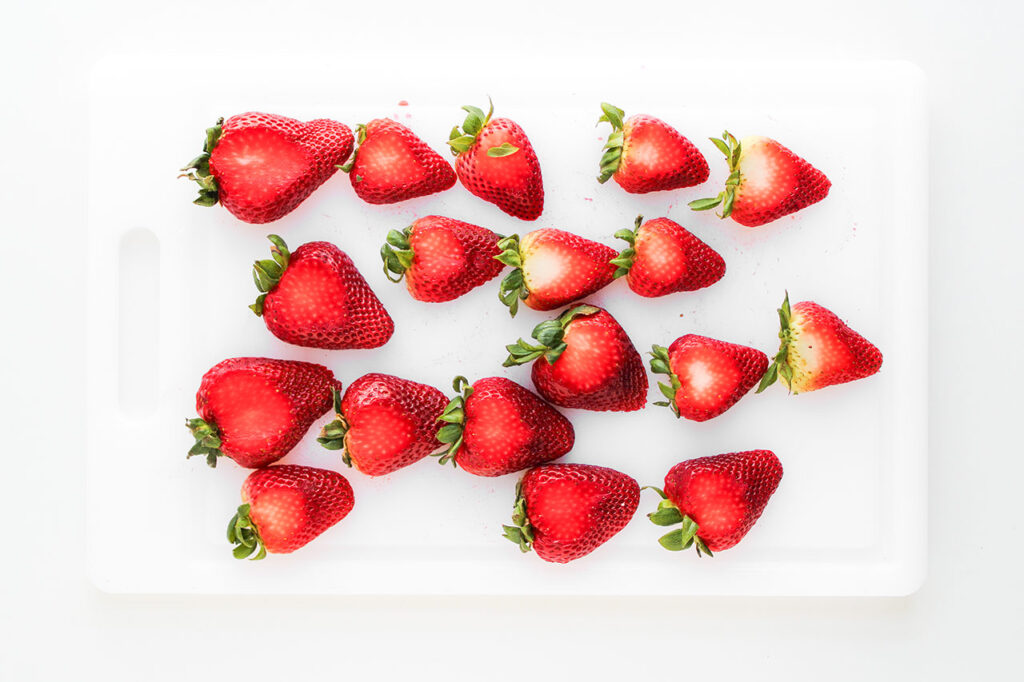 Whole strawberries on a white cutting board. Overhead focus.