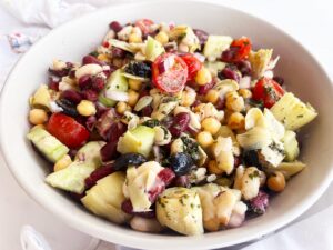 Front view of a white bowl with a serving of Mediterranean Dense Bean Salad.