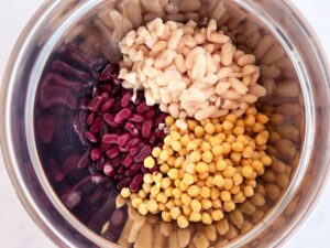 Overhead focus. Three types of beans in a metal mixing bowl.