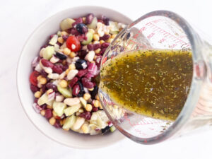 Adding dressing to the Mediterranean Dense Bean Salad.