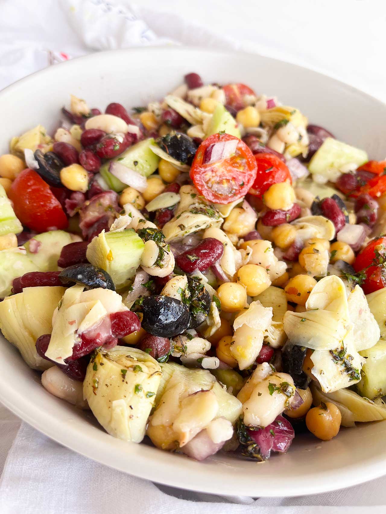 Front view of Mediterranean Dense Bean Salad in a white bowl.