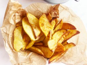 Baked potato wedges inn a parchment-lined basket.