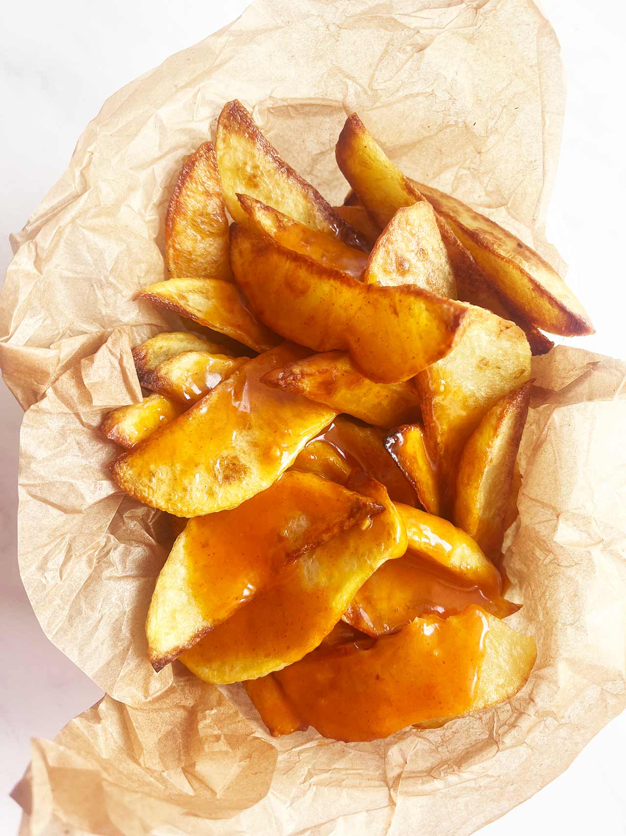 Overhead view of a parchment-lined basket filled with Patatas Bravas..