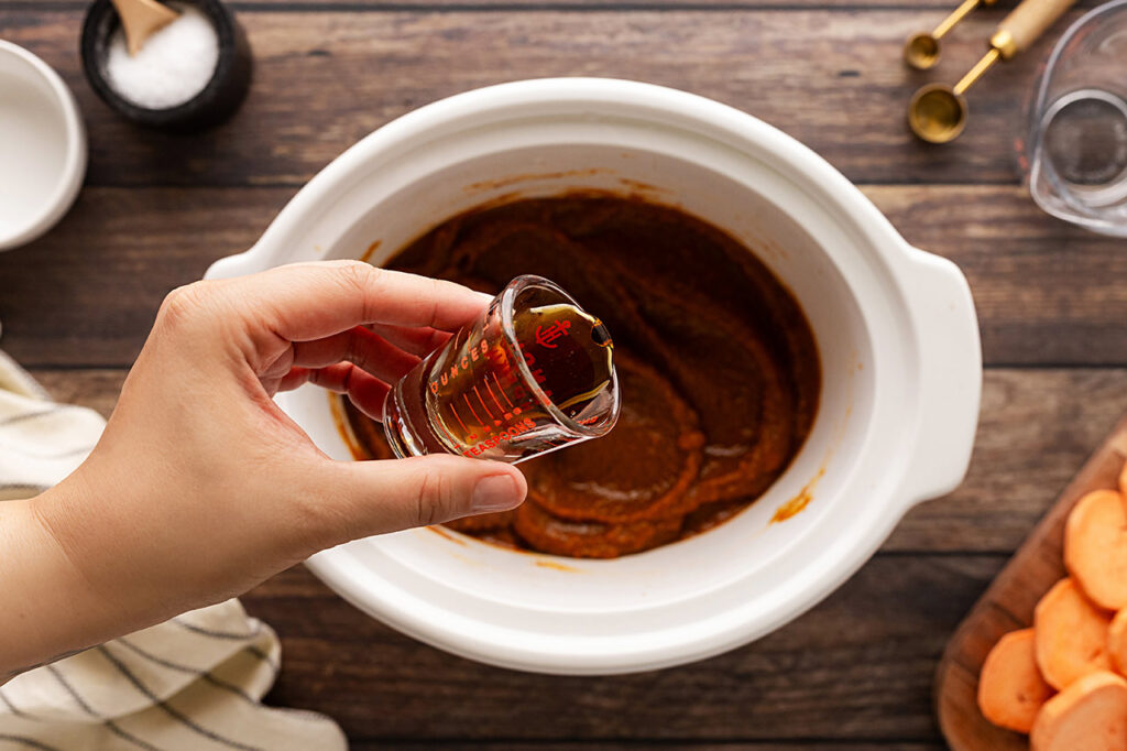 Adding sweetener to Sweet Potato Butter in a slow cooker crock.