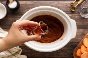 Adding sweetener to Sweet Potato Butter in a slow cooker crock.