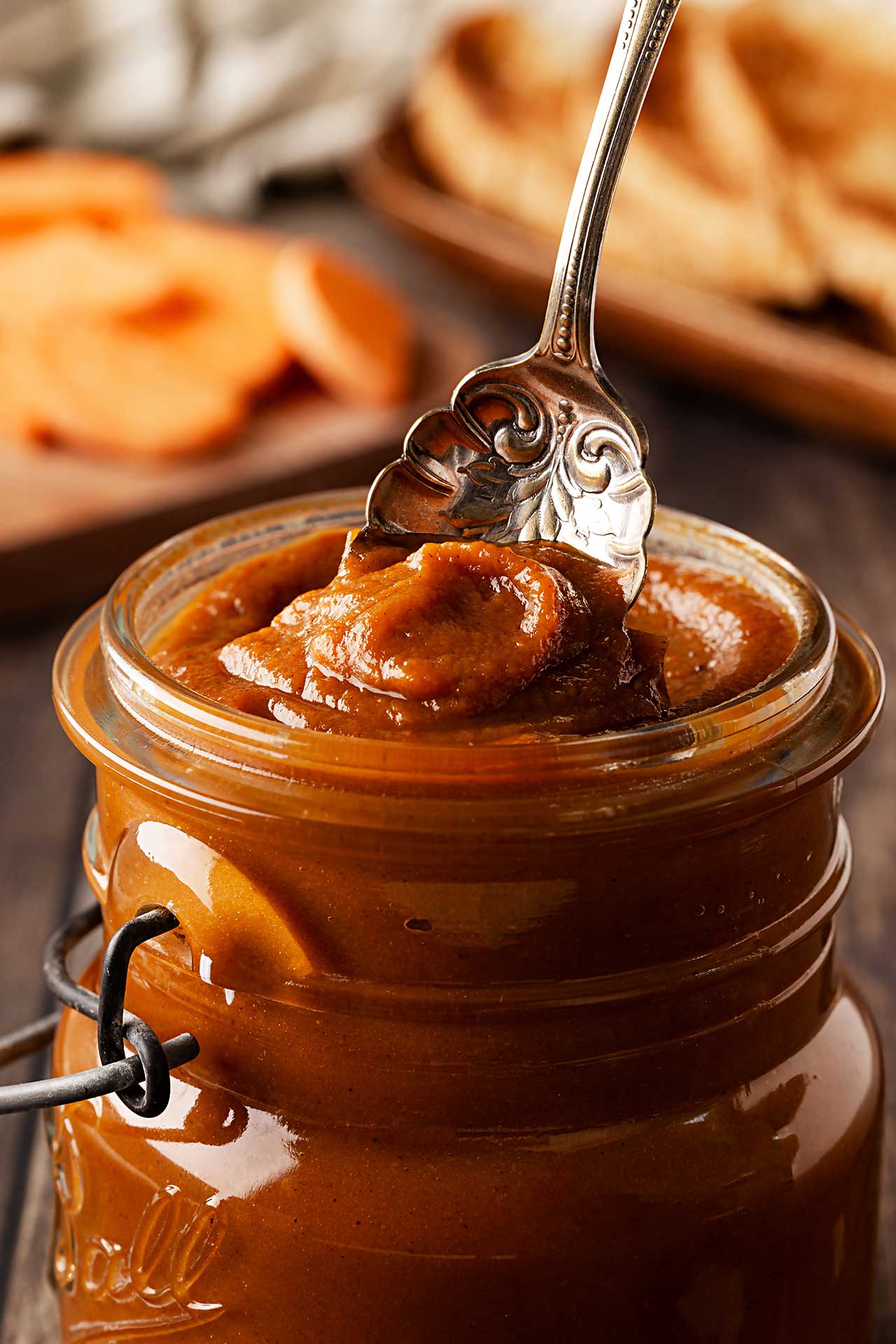A vintage spoon dips into an open jar of Sweet Potato Butter.