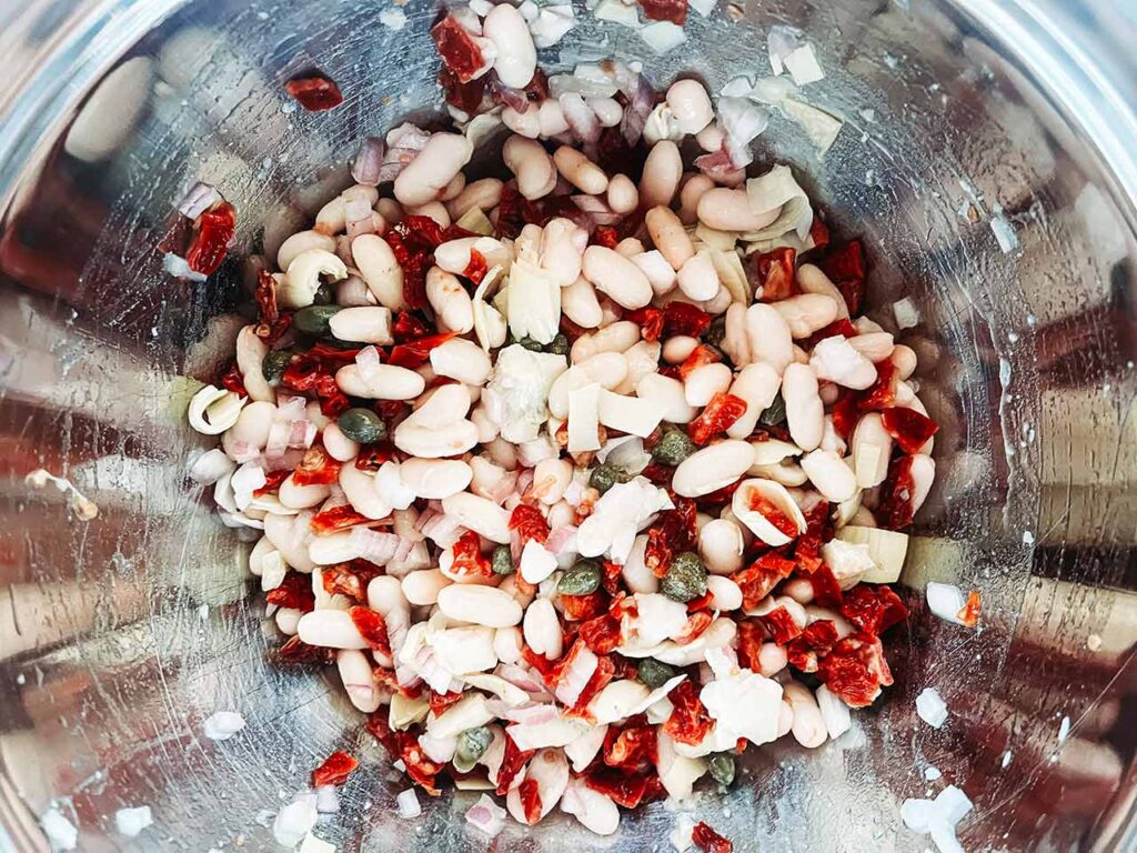 The tossed Tuscan White Bean Salad in a metal mixing bowl.
