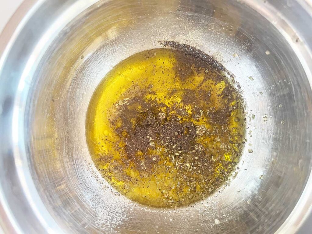 The unmixed dressing ingredients in a metal mixing bowl.