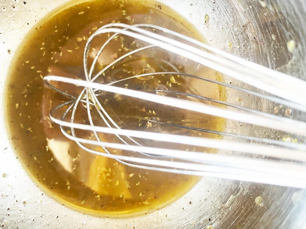 The mixed dressing in a mixing bowl with a whisk.