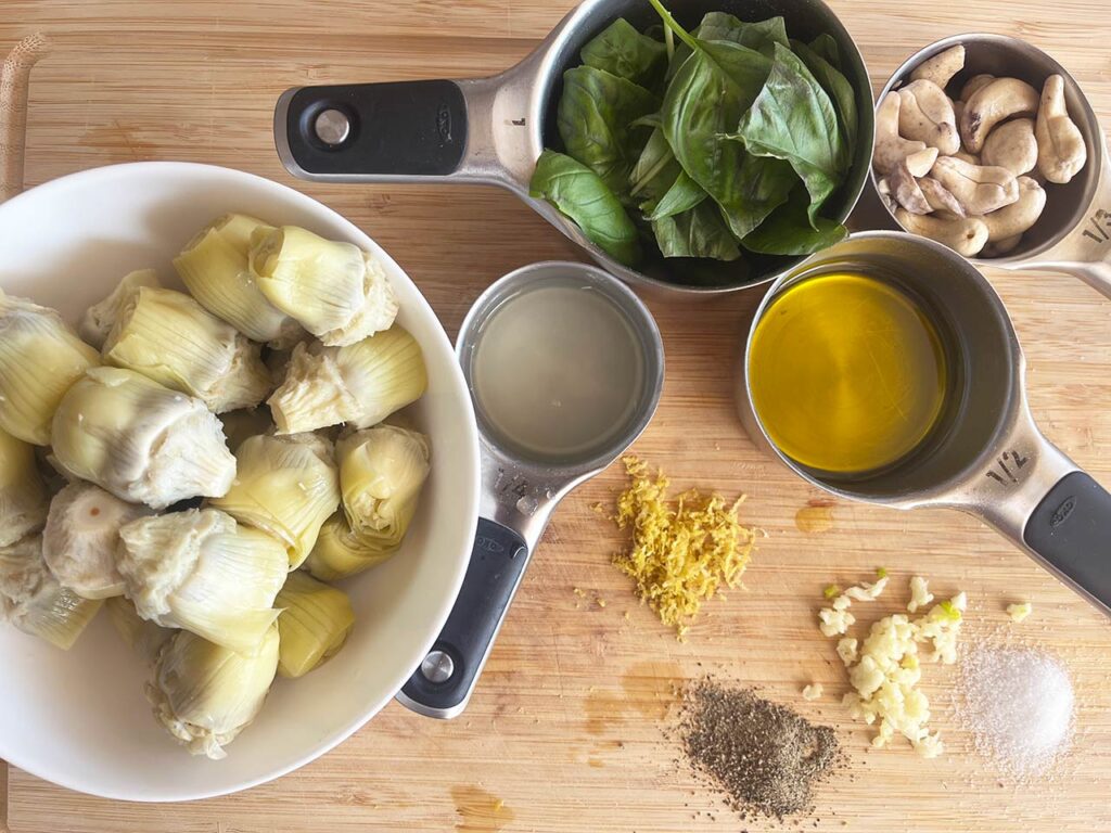 Artichoke Pesto ingredients gathered on a wood cutting board.