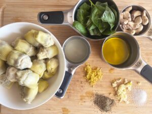 Artichoke Pesto ingredients gathered on a wood cutting board.