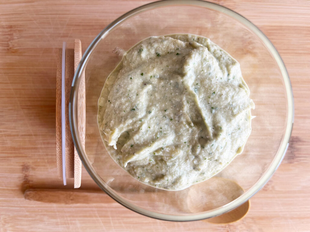 Overhead focus. Open jar of Artichoke Pesto on a wood surface.