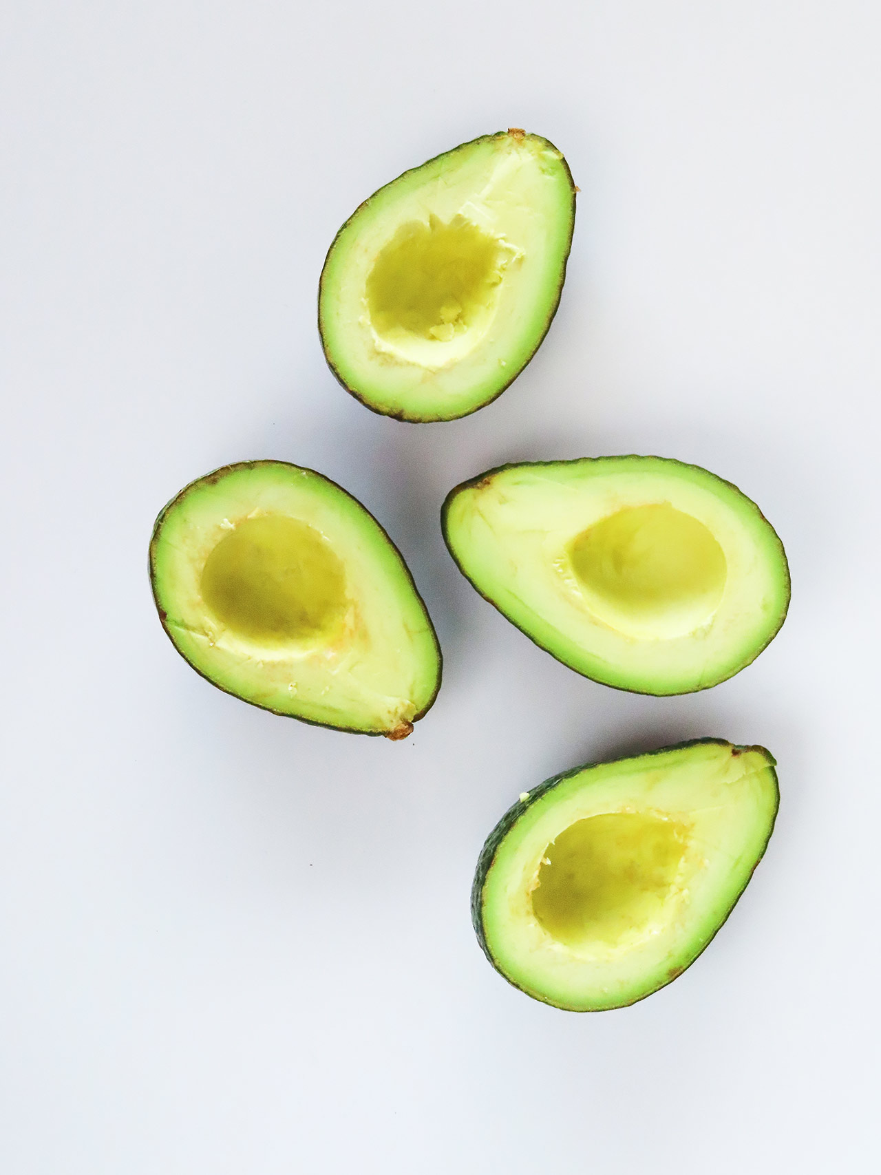 Cut avocados on a white surface.