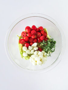 Caprese Stuffed Avocado salad ingredients in a mixing bowl.