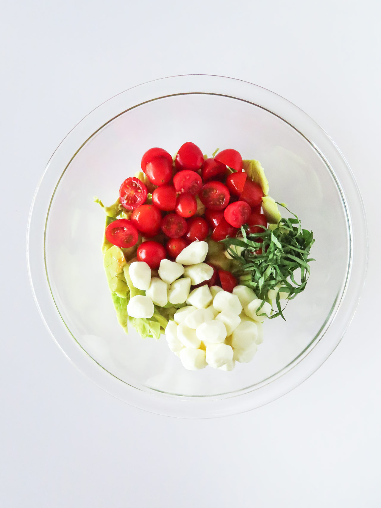 Caprese Stuffed Avocado salad ingredients in a mixing bowl.